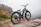 Close-up of a sleek ubco e-bike parked beside a rocky mountain path at sunset.
