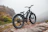 Close-up of a sleek ubco e-bike parked beside a rocky mountain path at sunset.