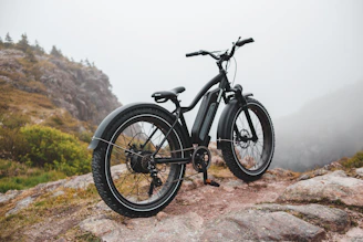 A sleek Ubco mountain bike parked on a rocky trail at sunrise.