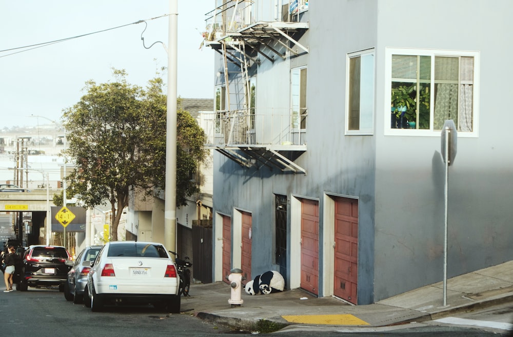 white car parked beside white building during daytime