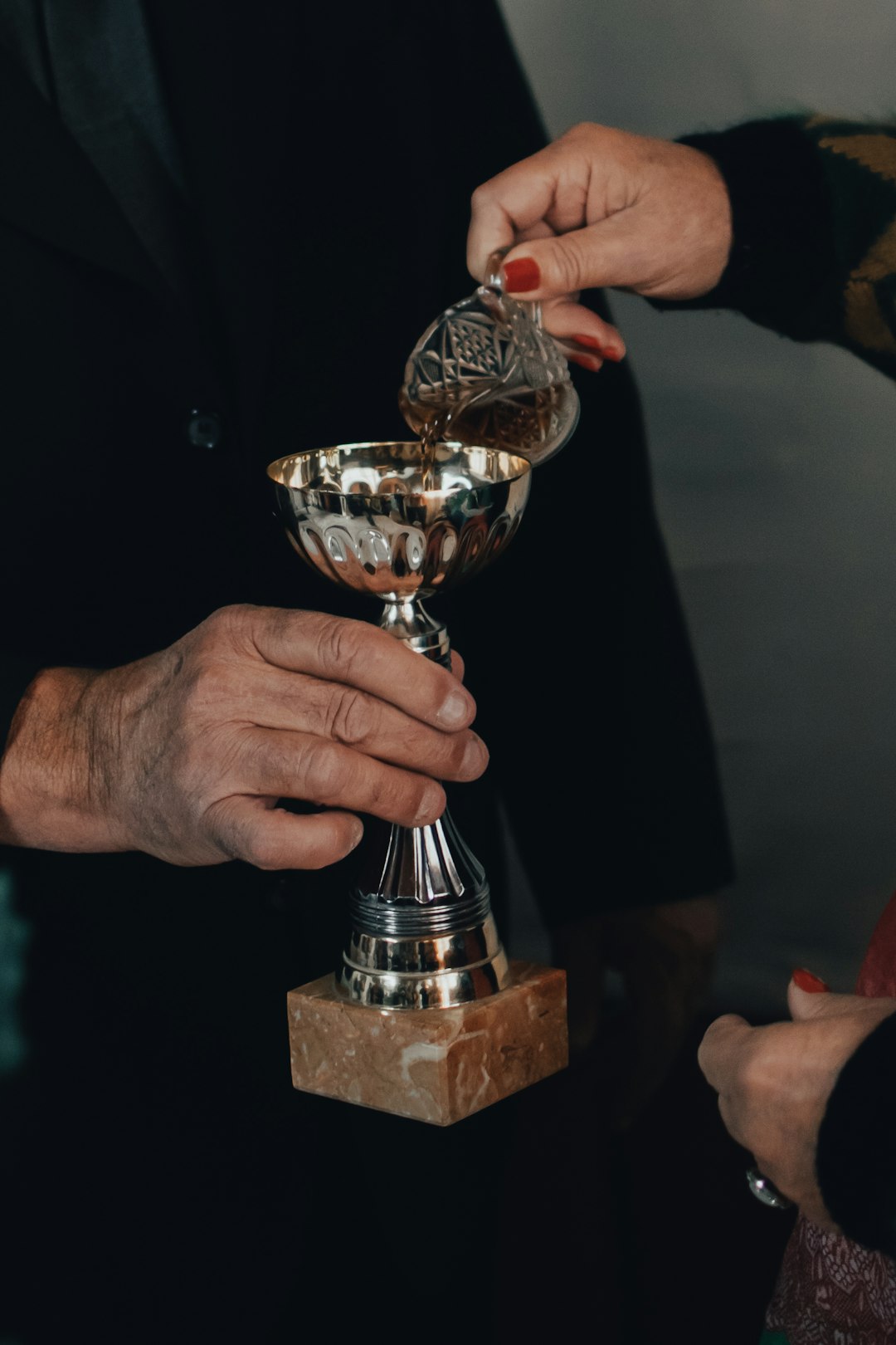 person holding gold trophy on brown wooden table