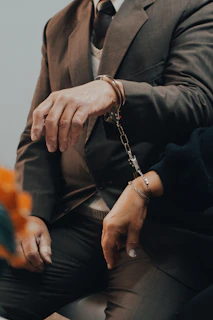 man in black suit jacket wearing silver chain bracelet