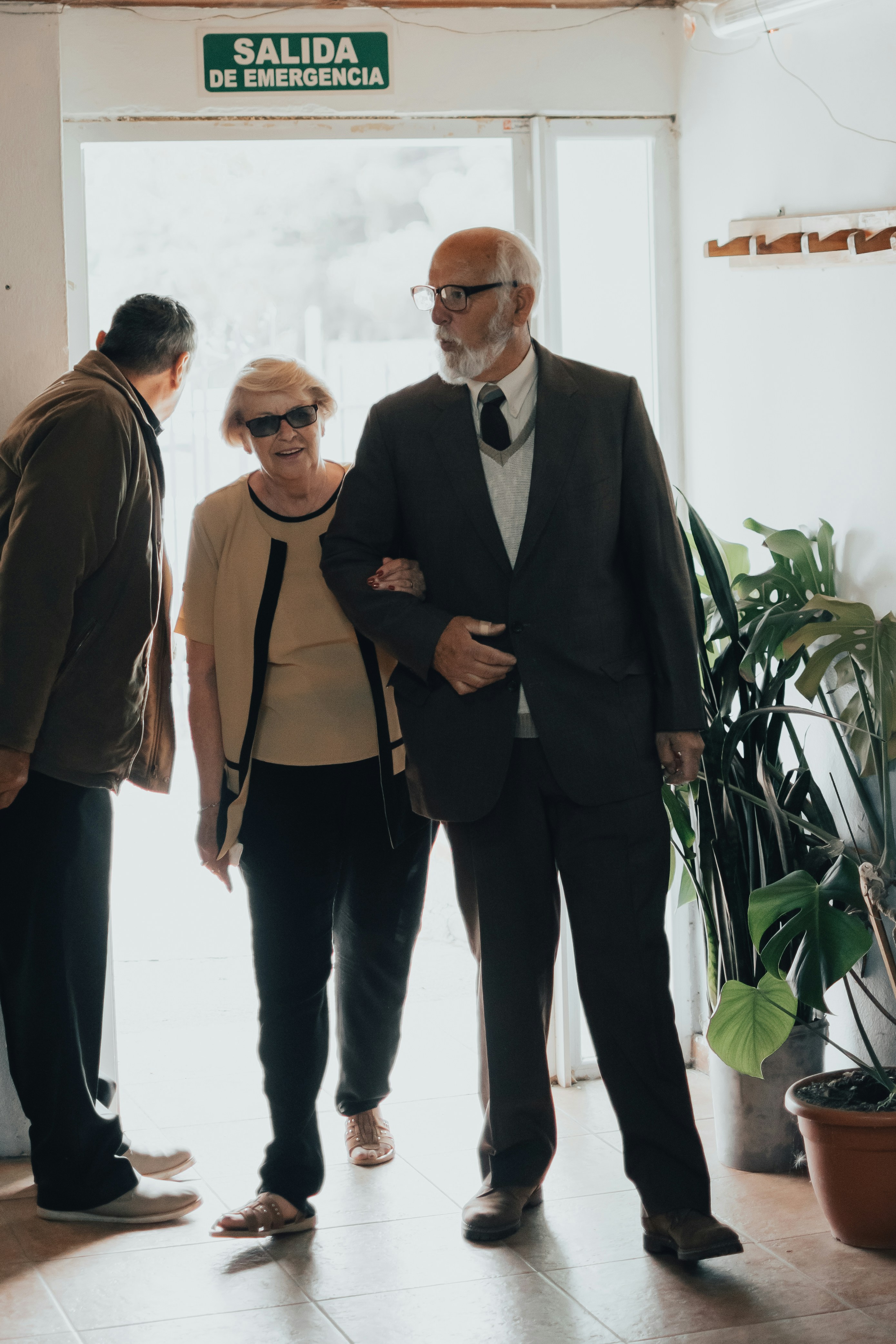 A senior associate in a navy suit reviewing a will with an elderly couple in a Pirie Street Adelaide office