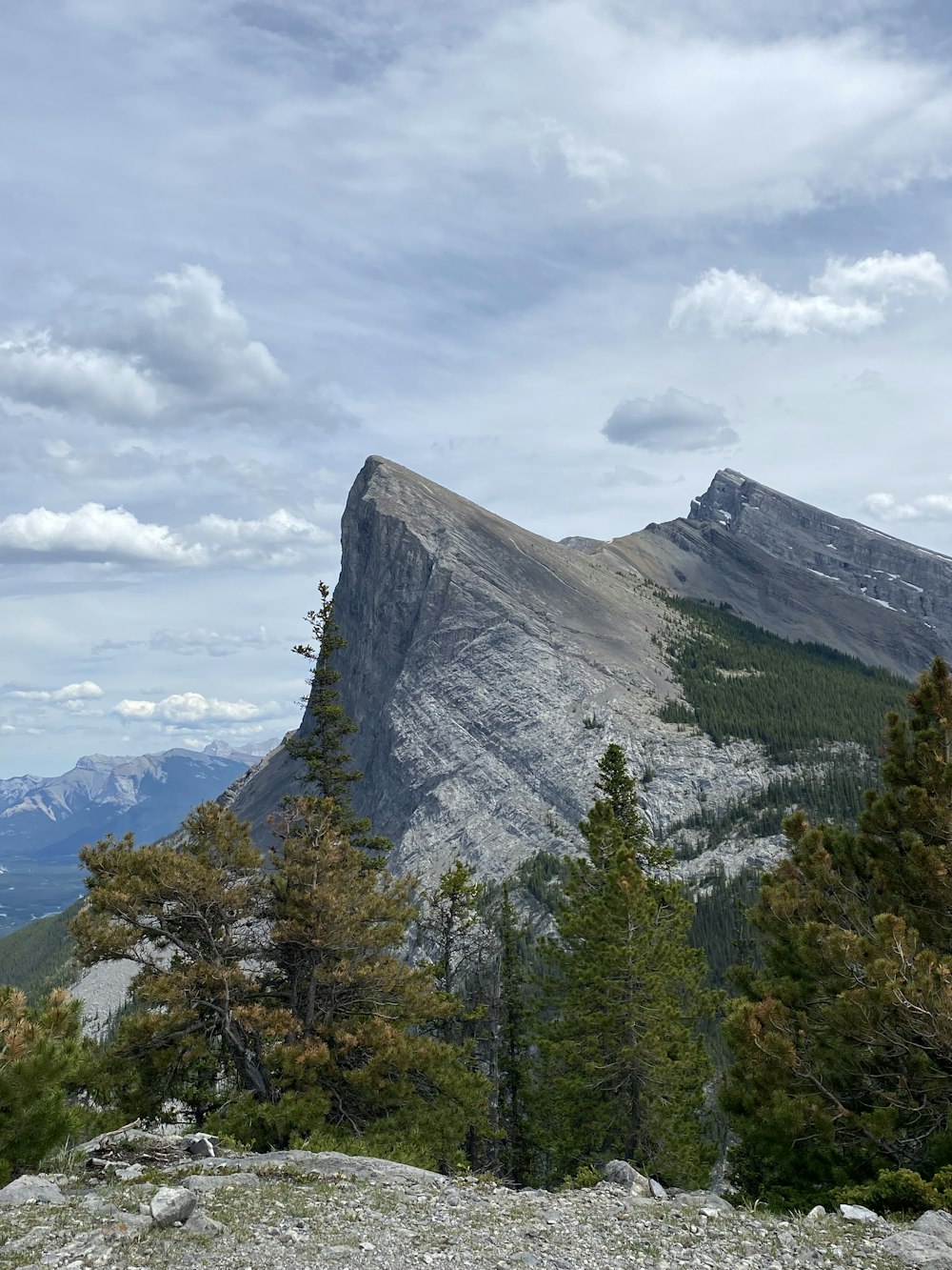 green trees near mountain under white clouds during daytime