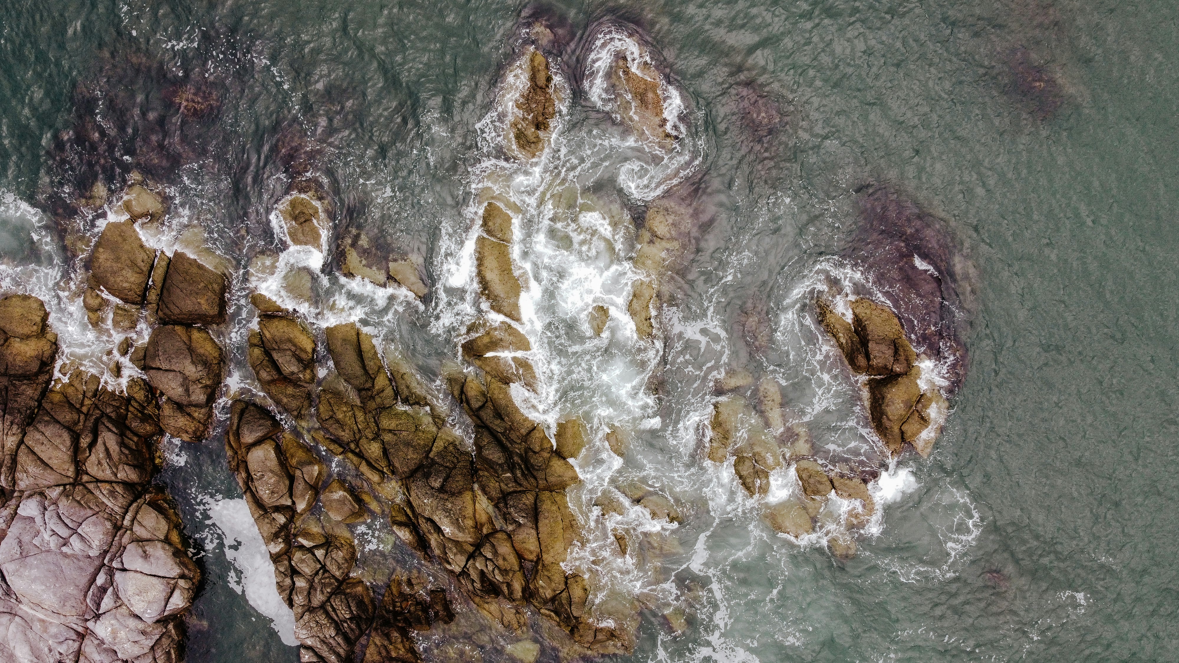 brown and white rock formation on body of water