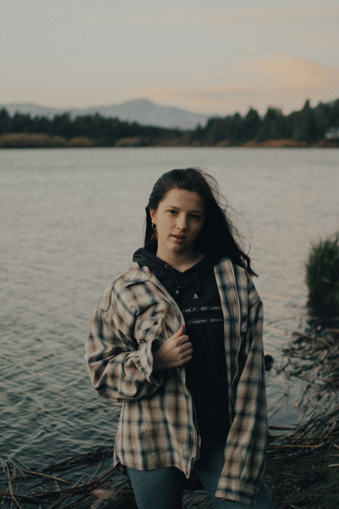 woman in black and white checkered coat standing near body of water during daytime