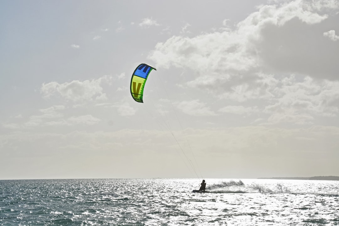 person surfing on sea under white clouds during daytime