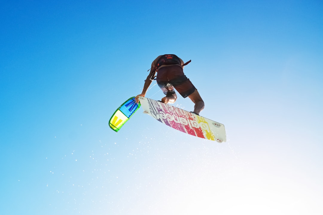 man in black shirt riding on white and red surfboard during daytime