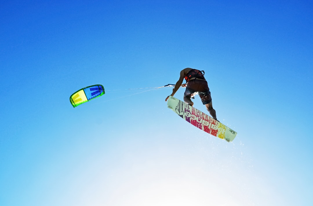 man in black jacket and blue pants riding green and yellow snowboard during daytime