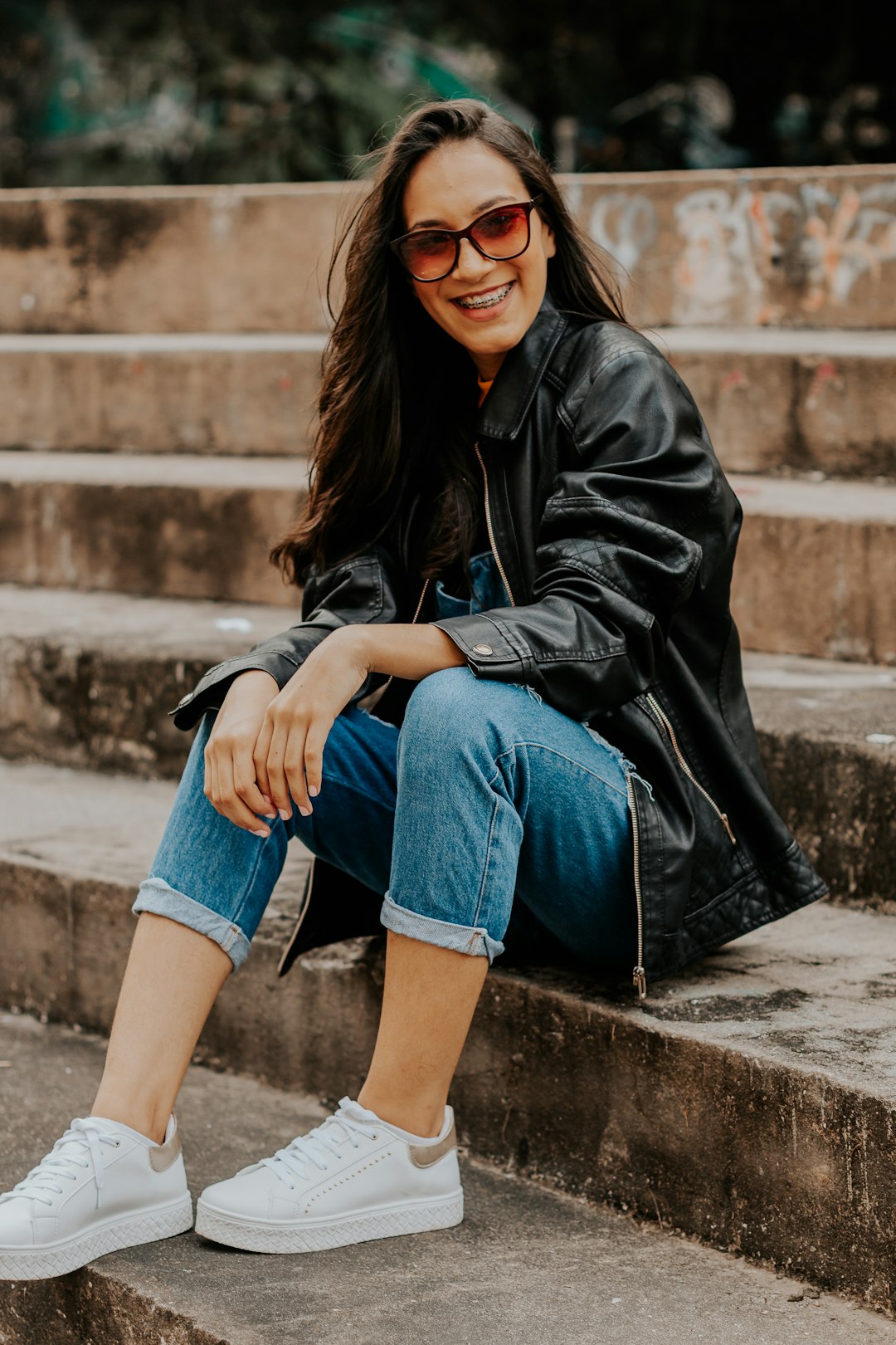 woman in black leather jacket and blue denim shorts sitting on concrete stair