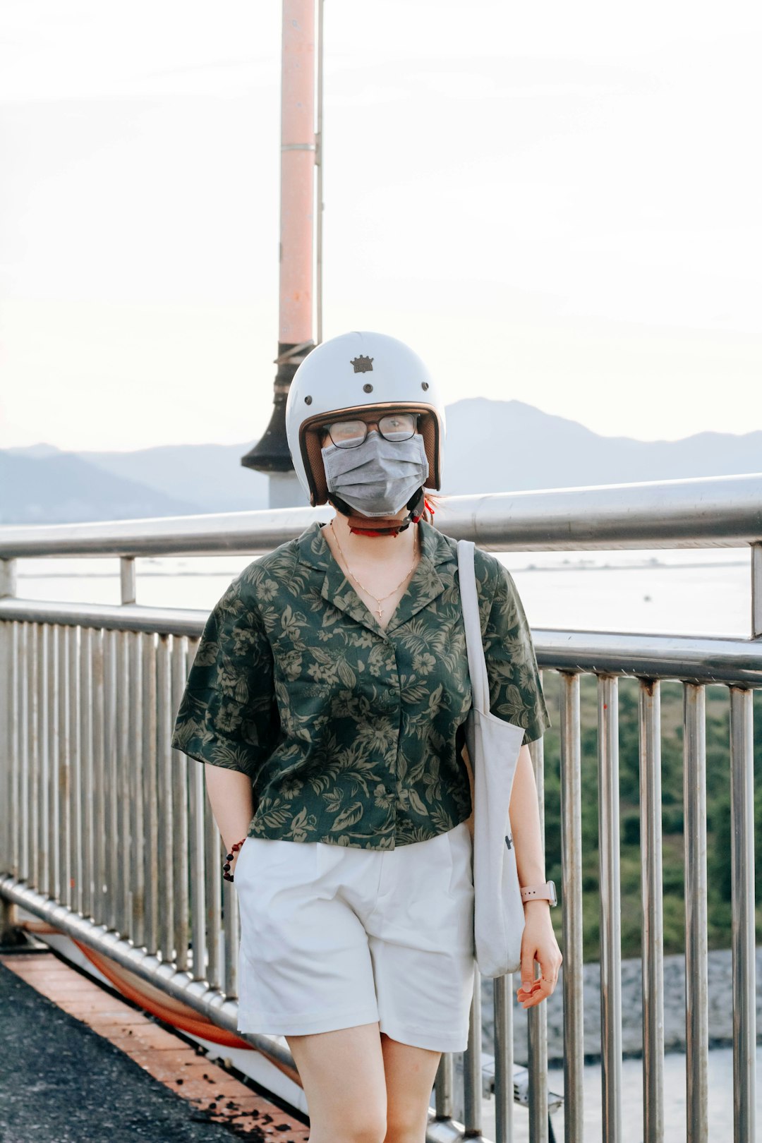 woman in green and black floral button up shirt and white pants wearing white helmet