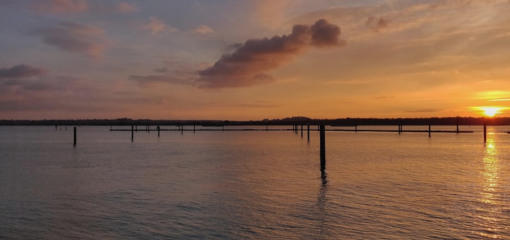 silhouette of dock on sea during sunset