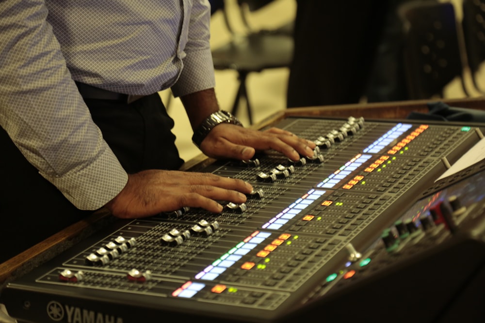 person in white and black checked shirt playing audio mixer