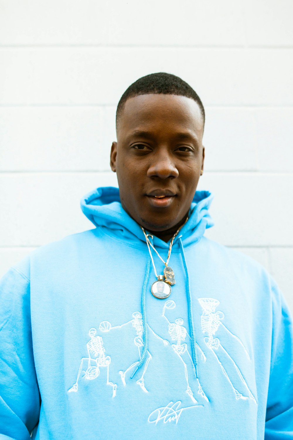 man in blue hoodie standing near white wall