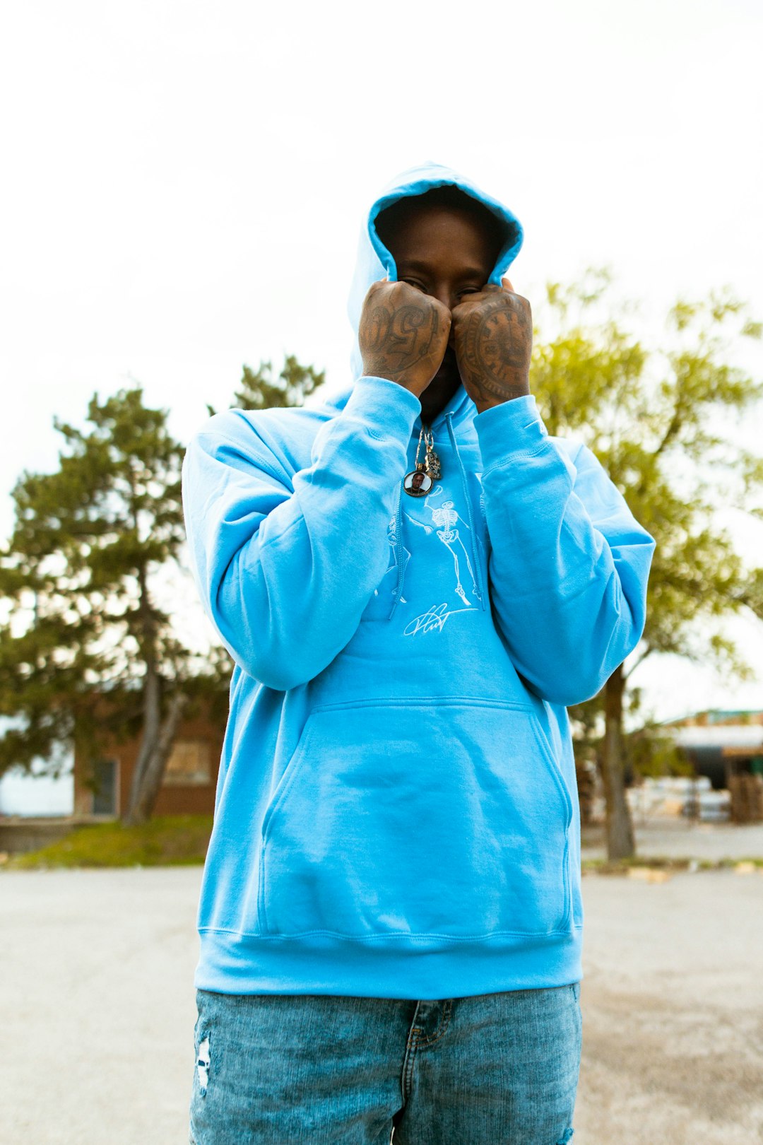 man in blue long sleeve shirt covering his face with his hand