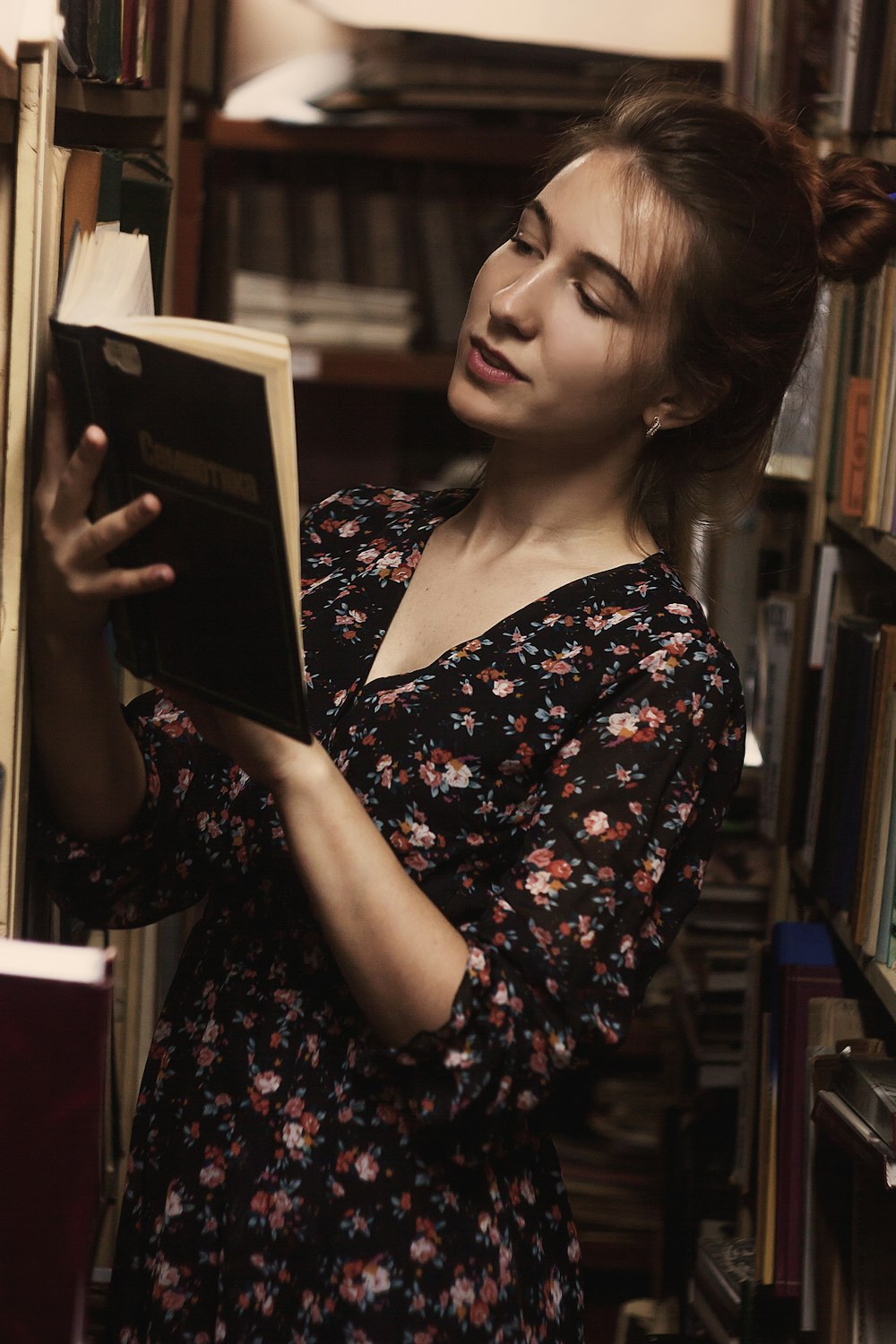 woman in black and red floral dress holding book