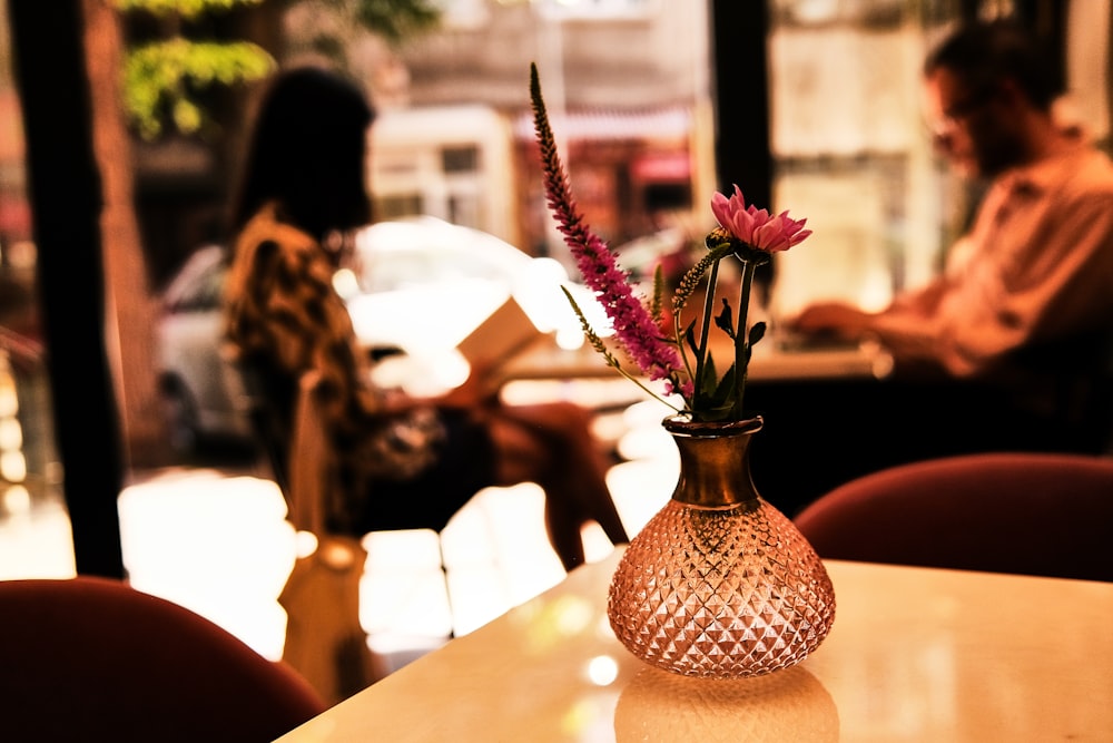 pink and white flowers in brown ceramic vase on table