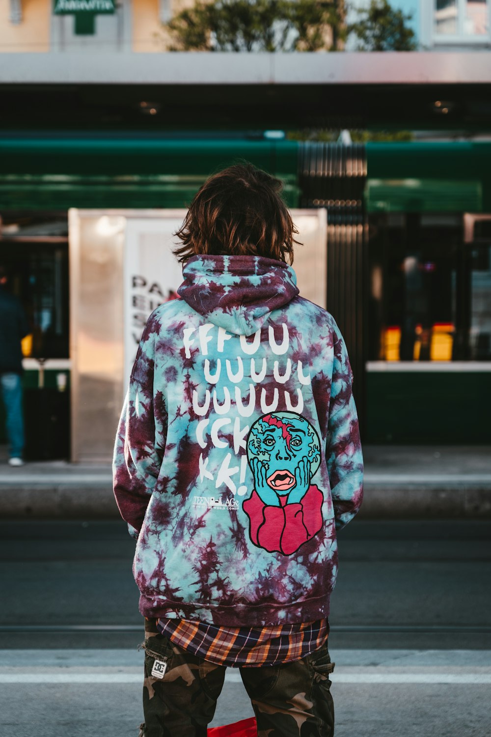 woman in white pink and blue floral hoodie standing on sidewalk during daytime