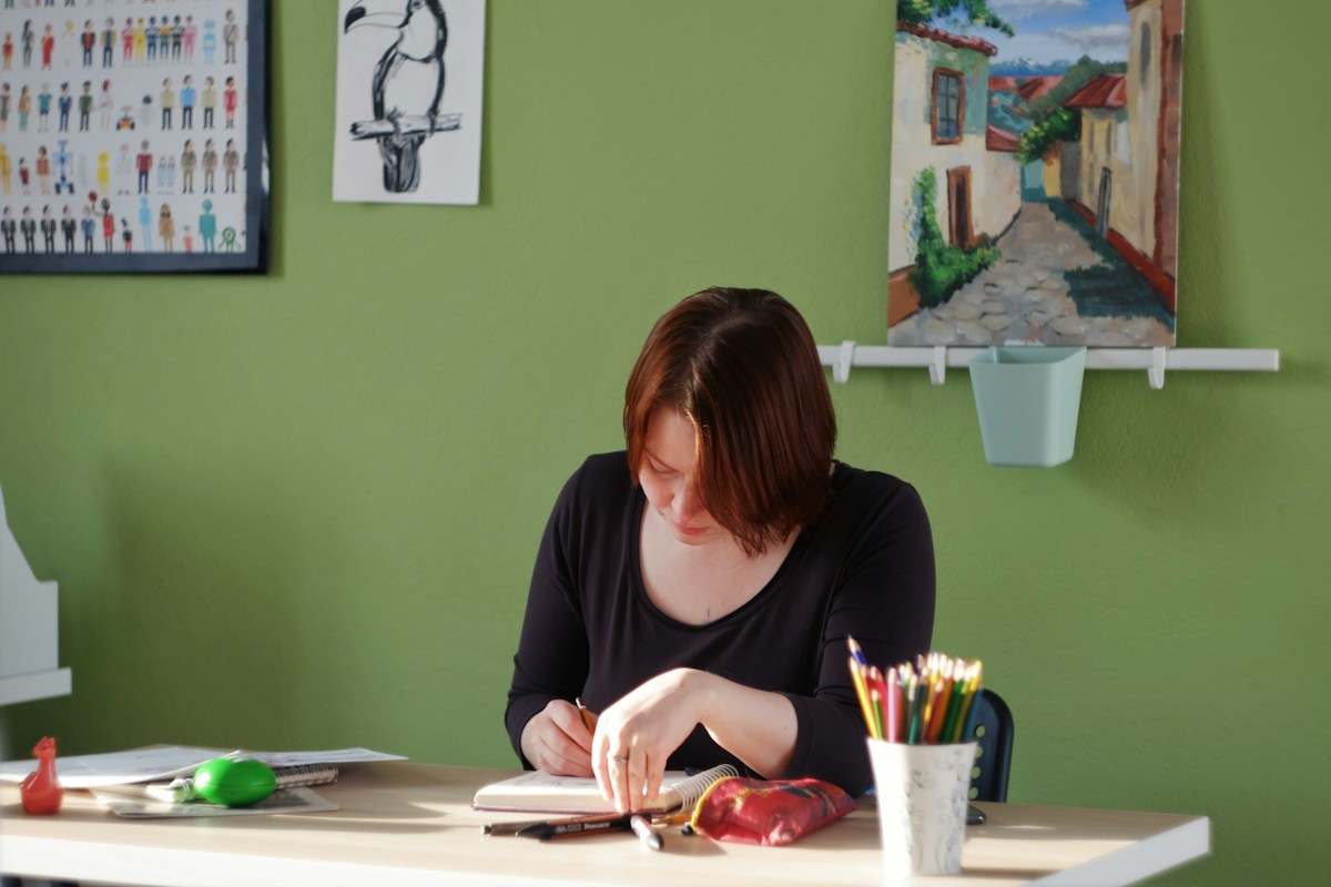 Woman in a black long sleeve shirt sits at a table, reviewing a nonprofit summer checklist during the slow season.