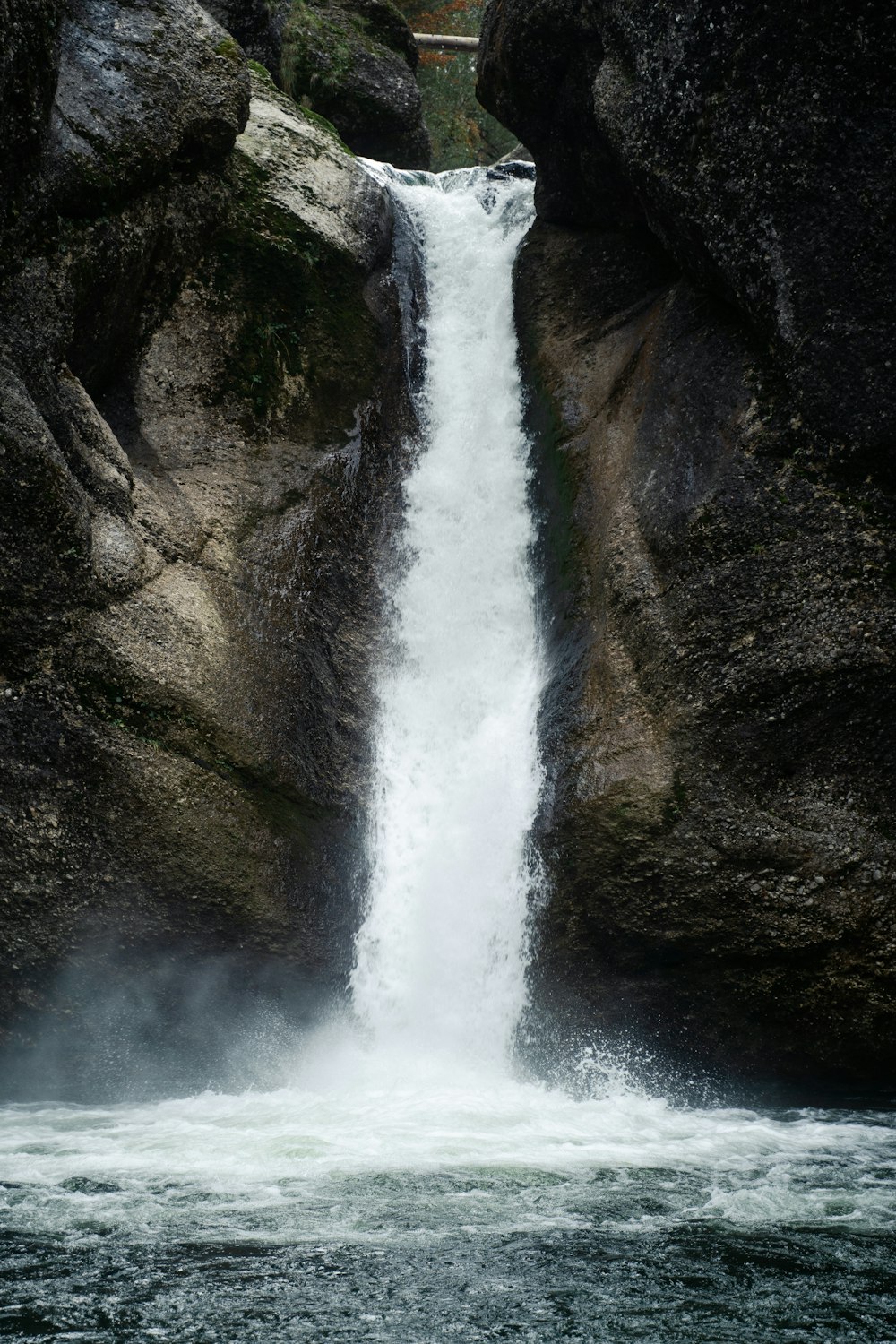 waterfalls between brown rocky mountain during daytime