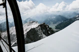 Close-up of a pilot smiling confidently mid-flight with rugged mountain peaks behind.