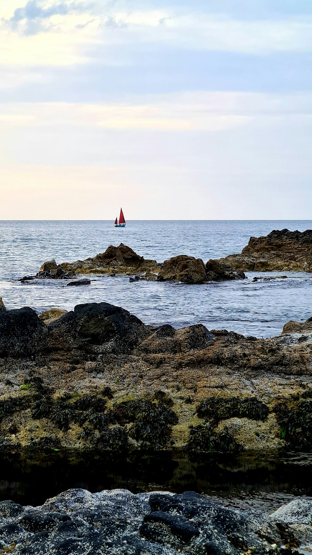 brown rocky shore with red and white flag on top during daytime