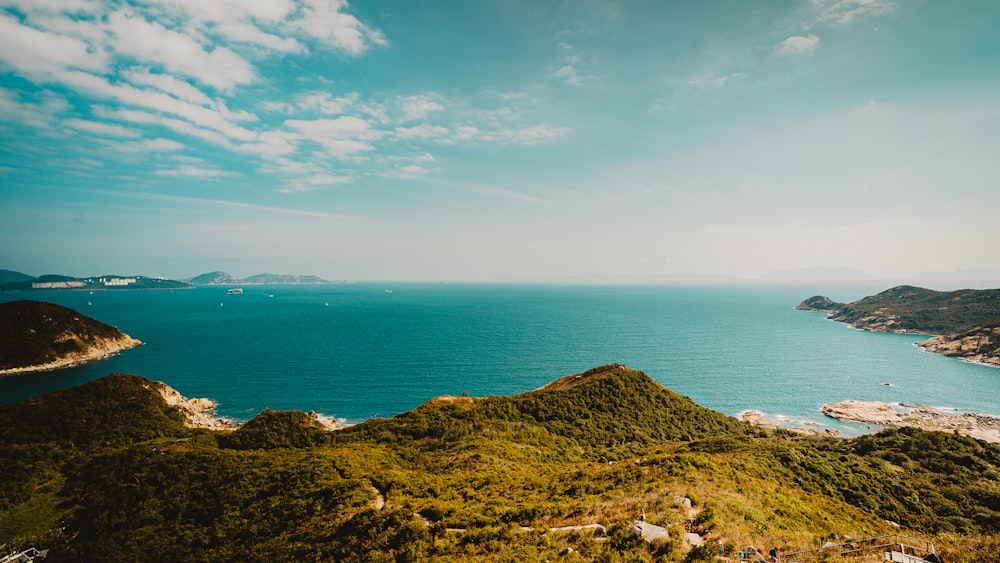 brown and green mountain beside blue sea under blue sky during daytime