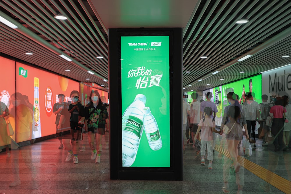 people walking inside building with green and white signage