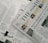 A section of a newspaper is placed over an open magazine. The newspaper displays a headline about the distribution of ex gratia finance and includes several smaller images and text flags. The magazine features articles and highlights, including historical and political content, with images and diagrams accompanying the text. The overall composition suggests a mix of current news and historical retrospectives.