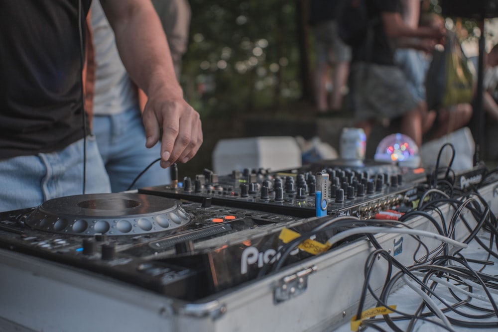 person in blue denim jeans standing in front of dj mixer