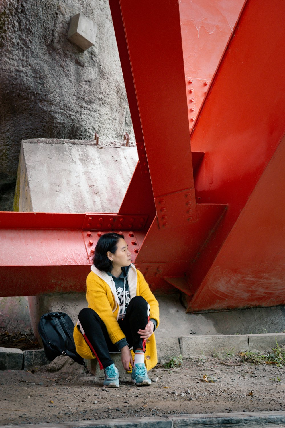 woman in yellow and black jacket sitting on concrete stairs