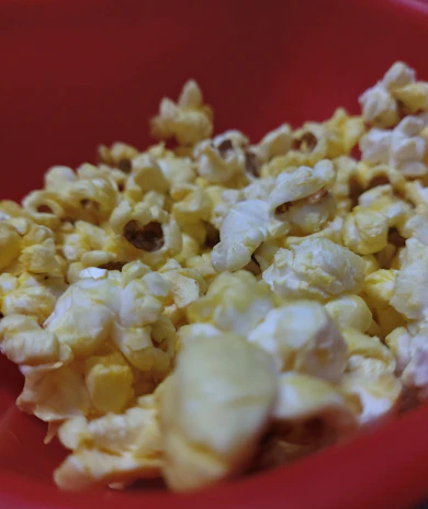 A close-up of buttery popcorn spilling from a vintage movie theater box.