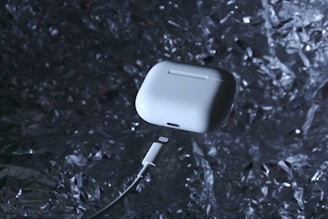 Close-up of a wireless earbud with a glowing blue charging case.