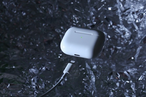 Close-up of a wireless earbud with a glowing blue charging case.