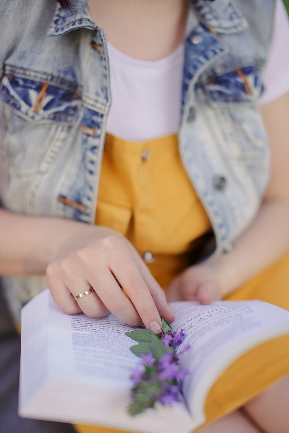 woman in blue denim jacket holding purple flower