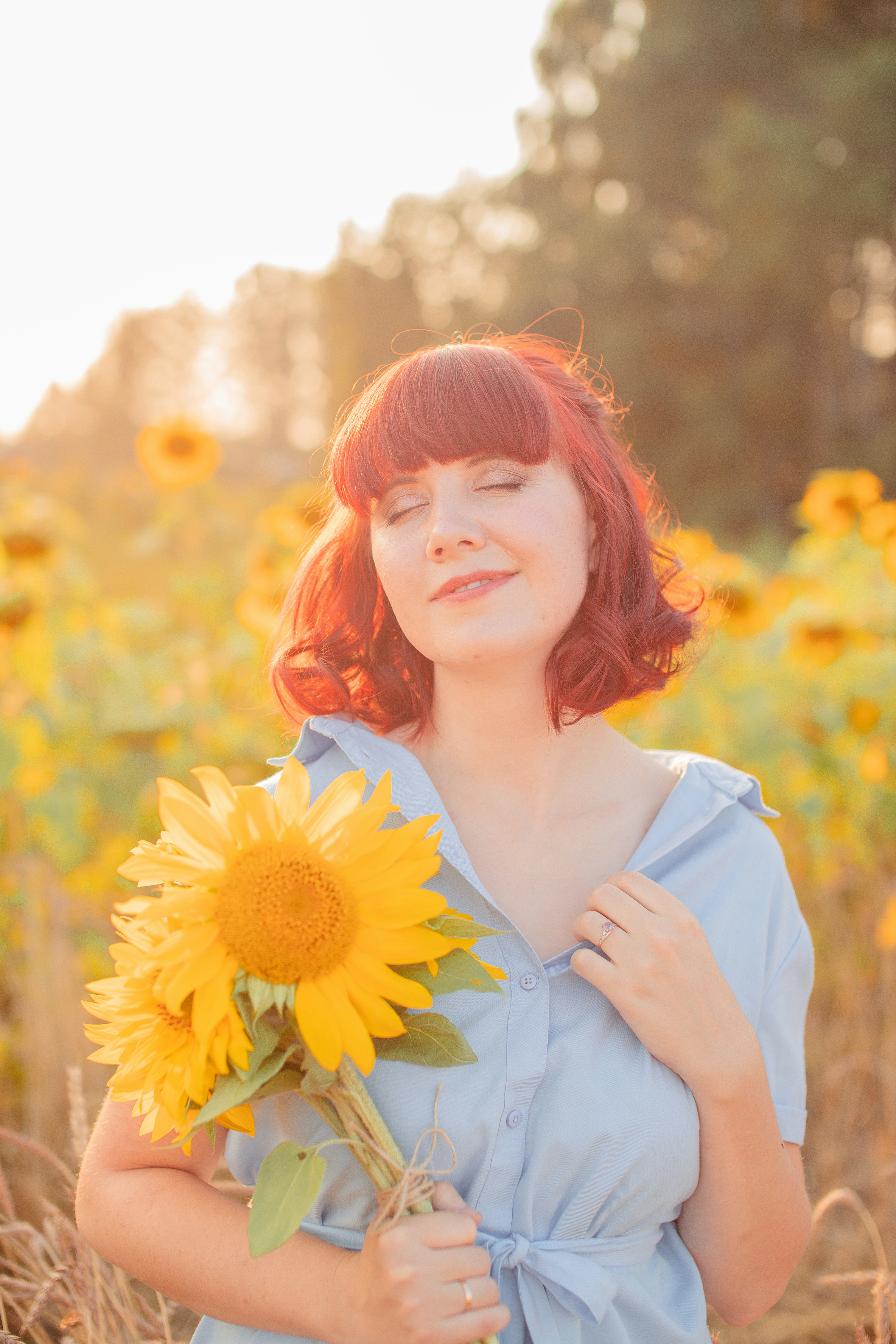 woman in white dress shirt holding yellow sunflower during daytime