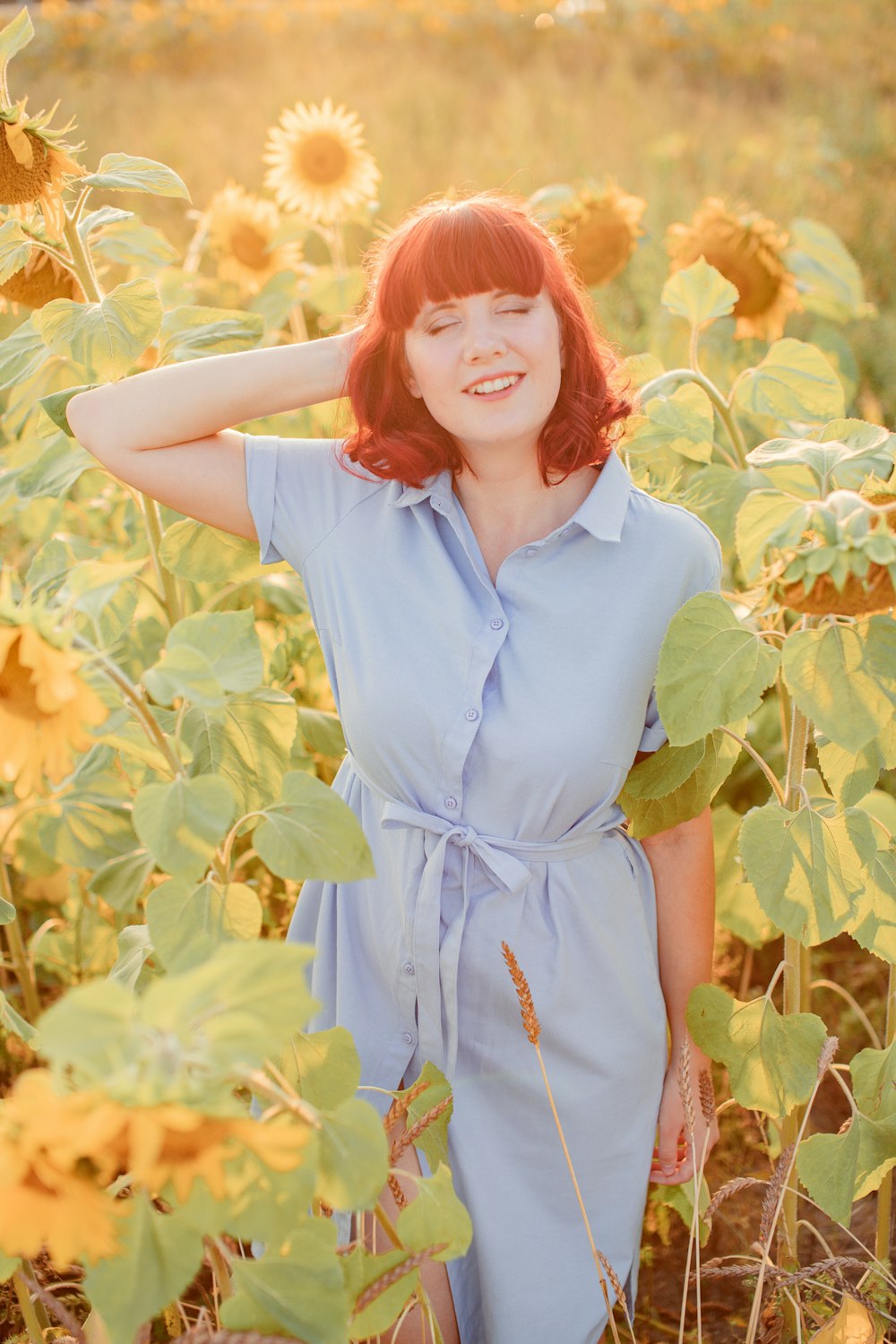 woman in blue button up shirt standing on yellow flower field during daytime