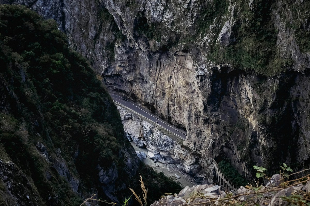 Looking down on a road cut between gorge cliffs above a riverbed