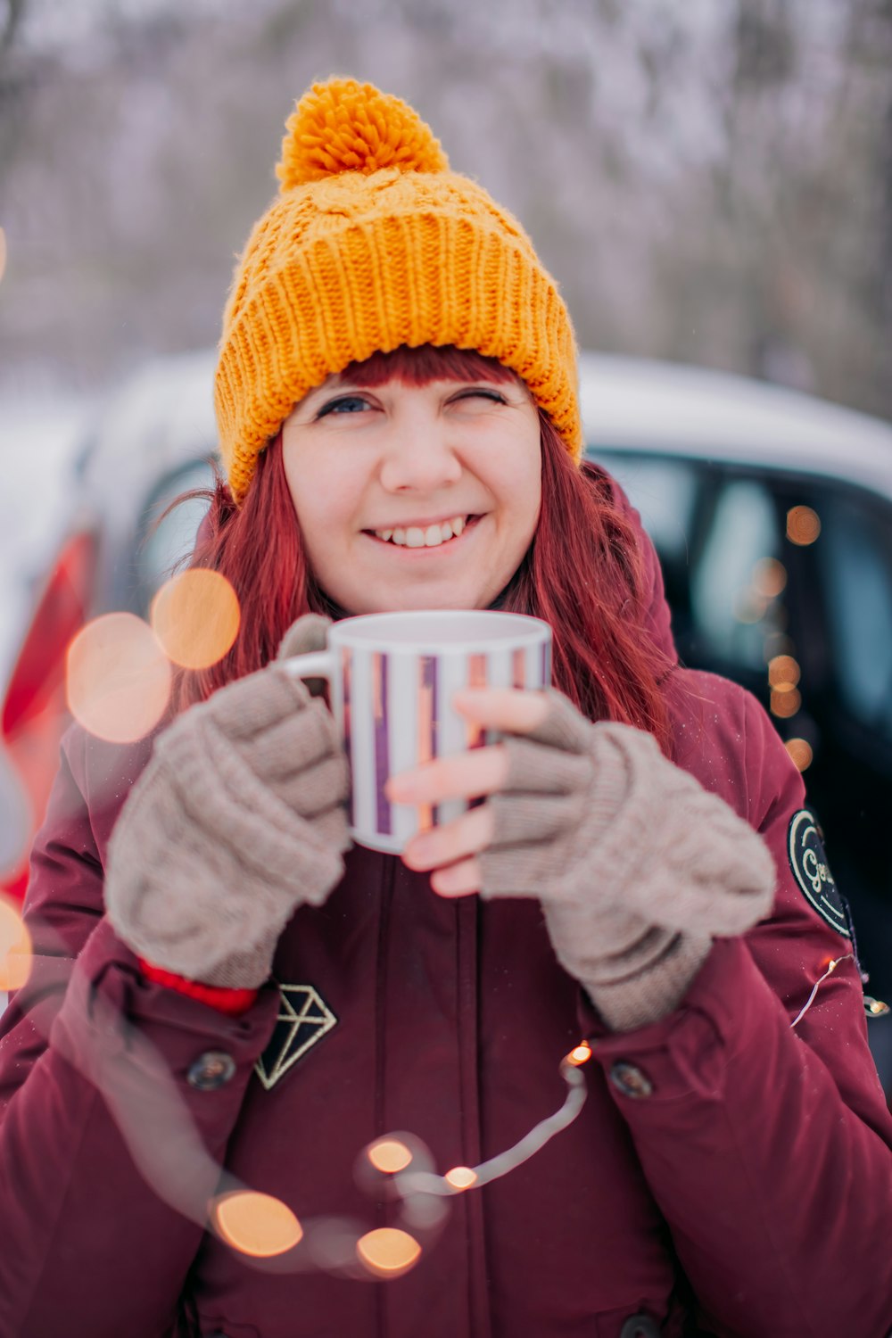 woman in brown knit cap holding white ceramic mug