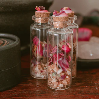 Handcrafted healing balms in small glass jars with botanical labels on a wooden table with dried flowers