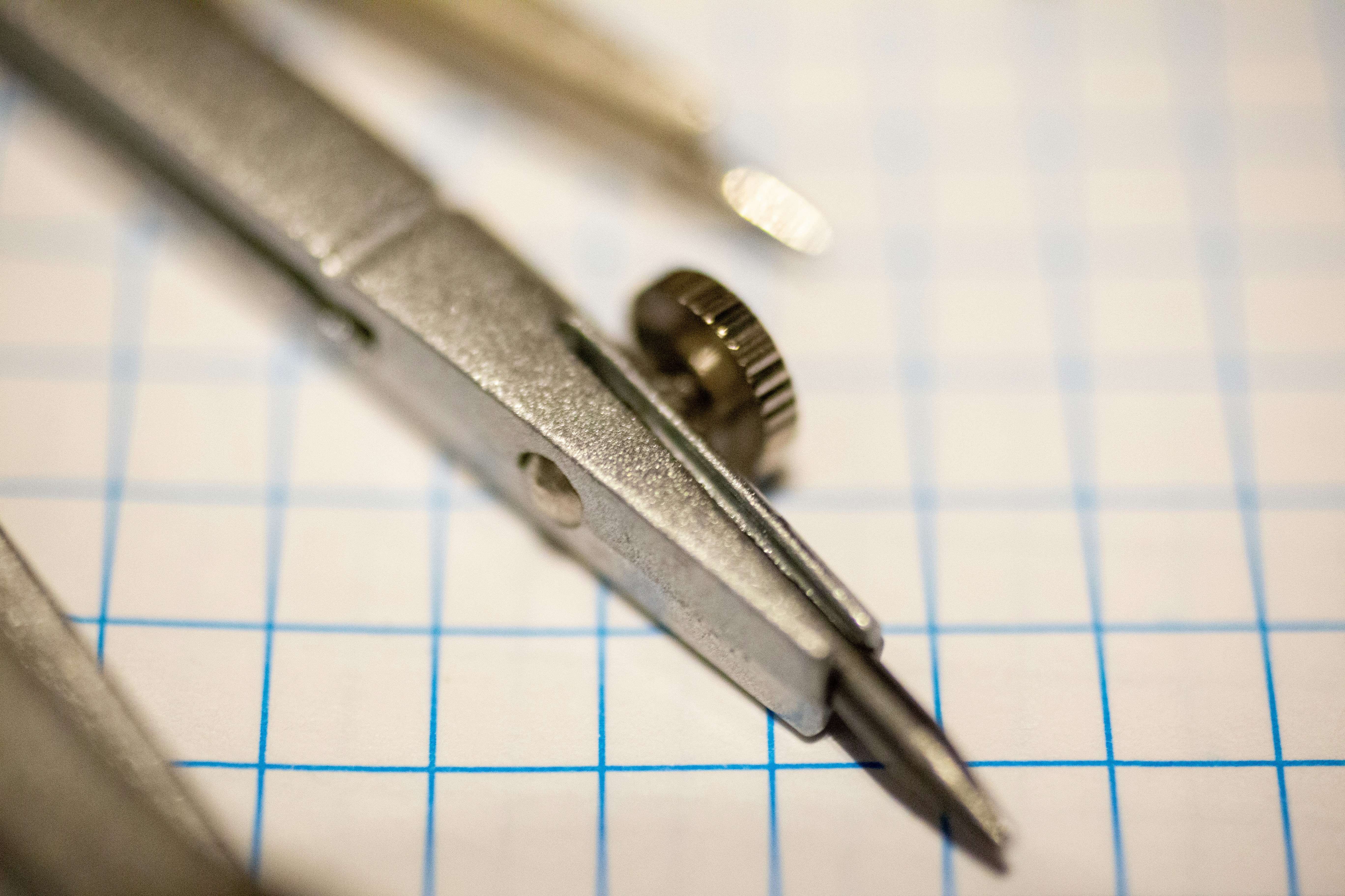 silver steel hand tool on white paper