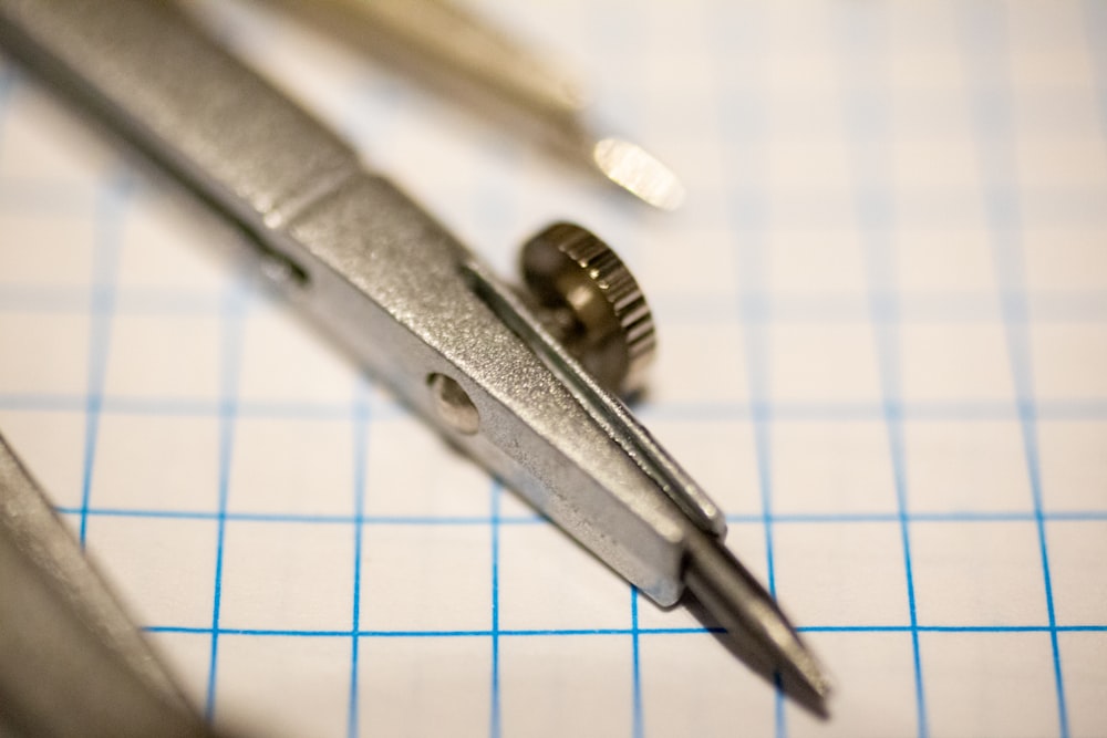 silver steel hand tool on white paper