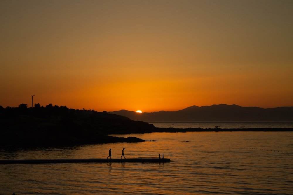 silhouette of people on sea during sunset