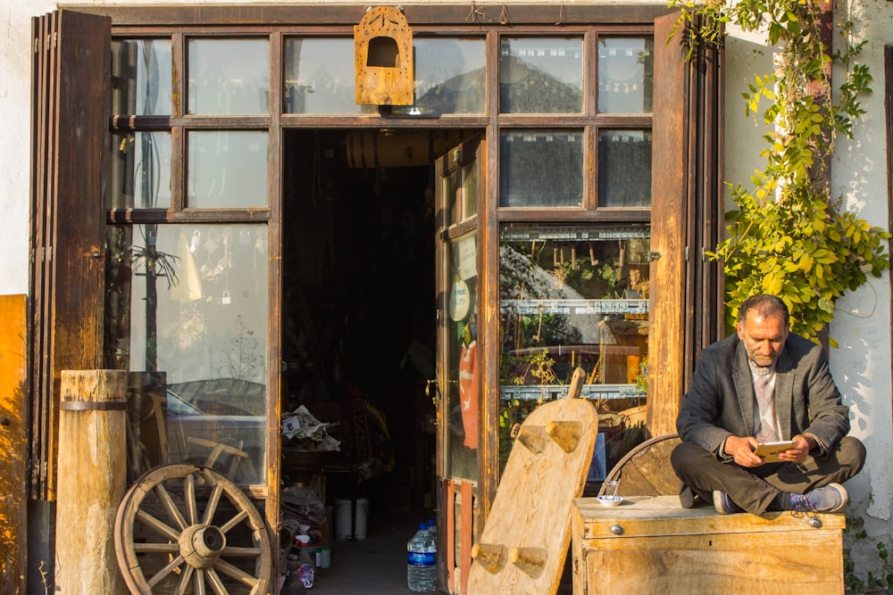 man in black jacket sitting on brown wooden chair