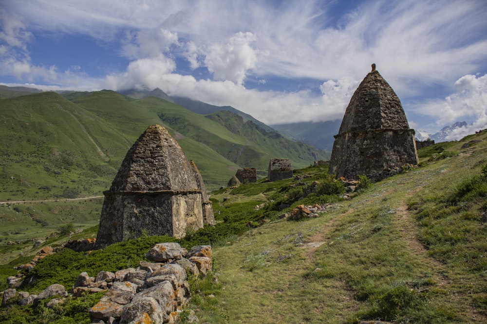 gray concrete house on green grass field near mountain under white clouds and blue sky during