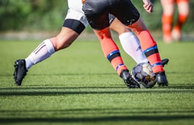 woman in black and white soccer jersey kicking soccer ball on green field during daytime