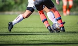 woman in black and white soccer jersey kicking soccer ball on green field during daytime