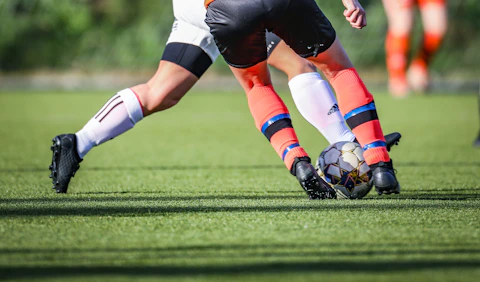 men in black and white soccer jerseys kicking soccer ball on green field during daytime