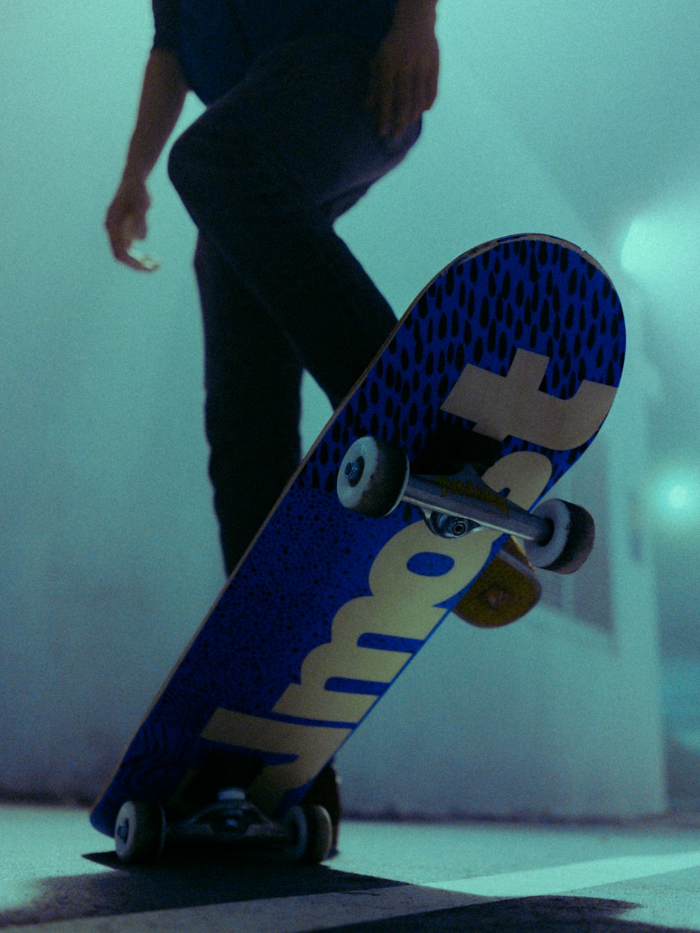 person in black pants standing on blue and white skateboard