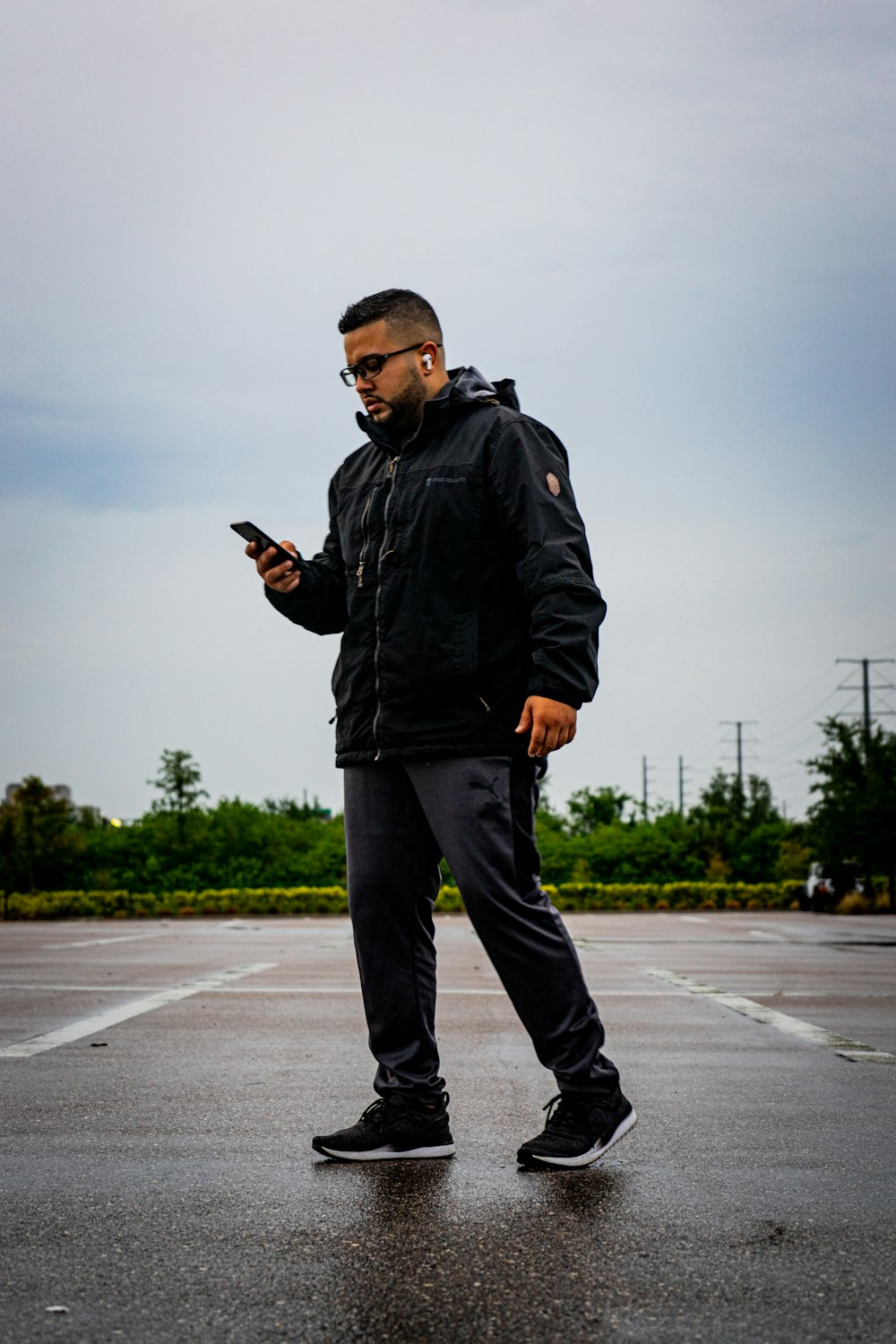 Hombre en chaqueta negra y pantalones negros de pie en la carretera durante el día